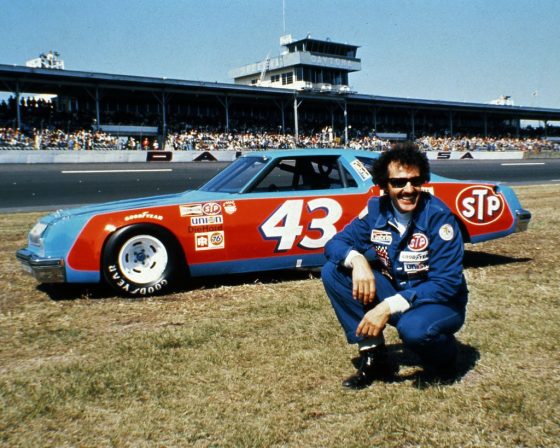 Richard Petty posing next to his car