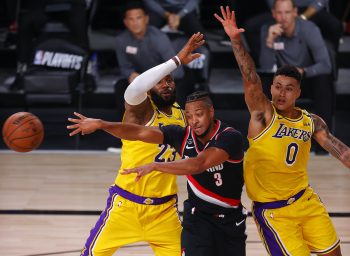 CJ McCollum of the Portland Trail Blazers passes the ball as LeBron James of the Los Angeles Lakers and Kyle Kuzma of the Los Angeles Lakers defend during the second quarter in Game One of the Western Conference First Round during the 2020 NBA Playoffs at AdventHealth Arena at ESPN Wide World Of Sports Complex on August 18, 2020 in Lake Buena Vista, Florida.