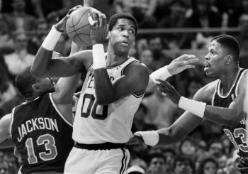 Robert Parish holds the ball between two defenders.