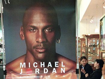 A salesgirl puts up a Michael Jordan cologne poster.