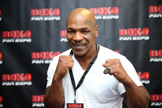 Former boxing champion Mike Tyson poses on the red carpet with his hands up in 2014