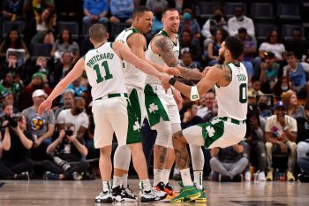 Payton Pritchard #11, Grant Williams #12 and Daniel Theis #27 help up Jayson Tatum of the Boston Celtics.