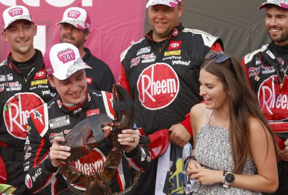 Christopher Bell accepts Loudon the Lobster, as his wife, Morgan Bell, looks on in Victory Lane after winning the NASCAR Cup Series Ambetter 301 at New Hampshire Motor Speedway on July 17, 2022.