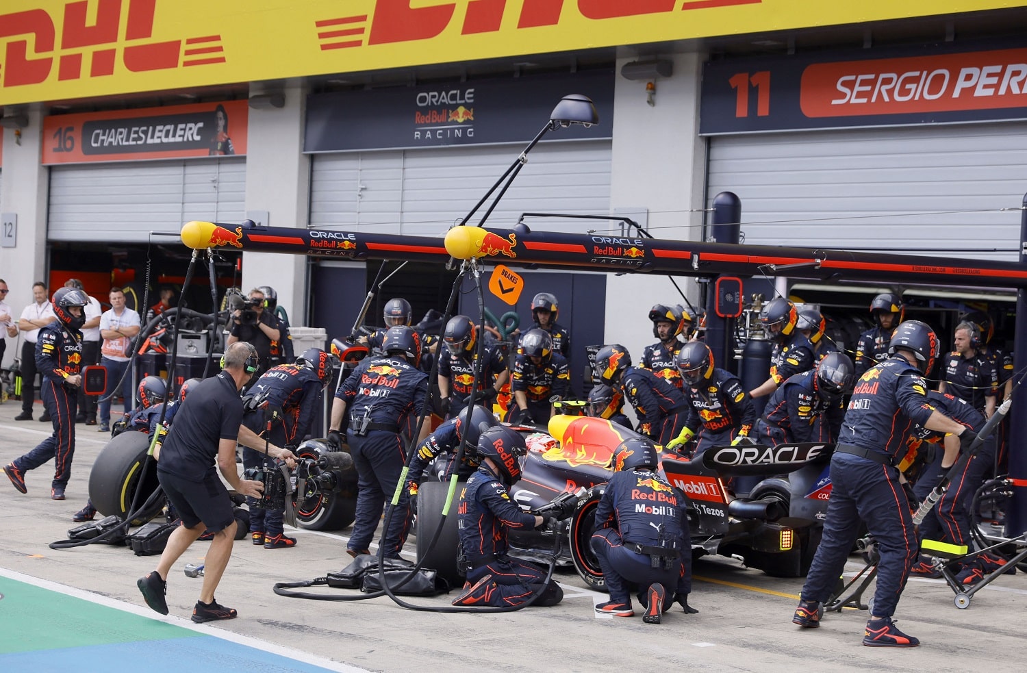 Technicians work on the car of Red Bull Racing's Sergio Perez at a pit stop on the Red Bull Ring race track in Spielberg, Austria, during the Formula 1 Austrian Grand Prix on July 10, 2022. | Ronald Wittek / AFP via Getty Images