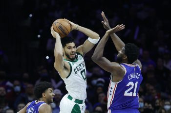 Jayson Tatum attempts a pass over Joel Embiid.