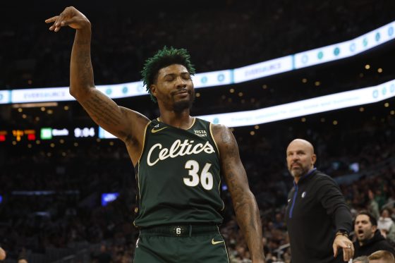 Marcus Smart of the Boston Celtics smiles at the Dallas Mavericks bench after hitting a three-point shot.