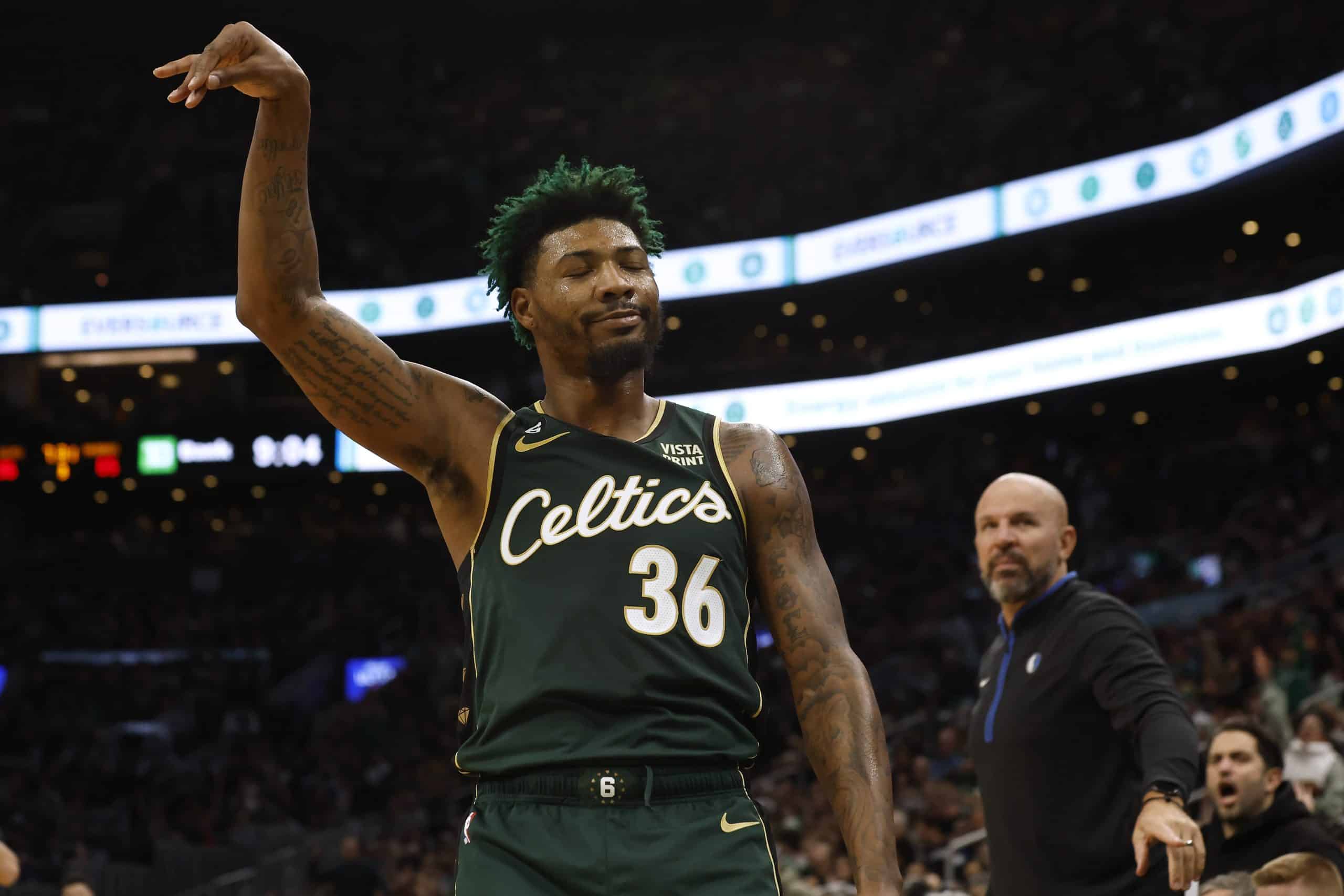 Marcus Smart of the Boston Celtics smiles at the Dallas Mavericks bench after hitting a three-point shot.