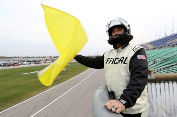 An official waves the caution flag from the flagstand during the NASCAR Xfinity Series Kansas Lottery 300 at Kansas Speedway on Oct. 17, 2020.