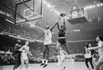 Boston Celtics center Bill Russell attempts to block the shot of Philadelphia 76ers star Wilt Chamberlain.