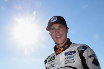 NASCAR driver Trevor Bayne walks off the track with the sun behind him