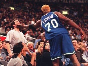 Mavericks player Dennis Rodman reaches out to owner Mark Cuban during an NBA game