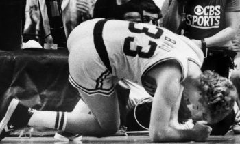 Larry Bird kneels in pain after injuring his leg.