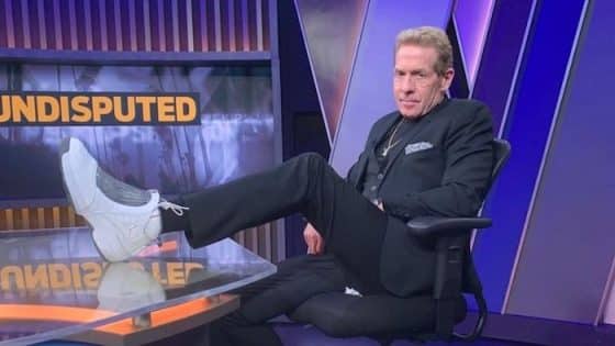 Skip Bayless sits down at a desk.